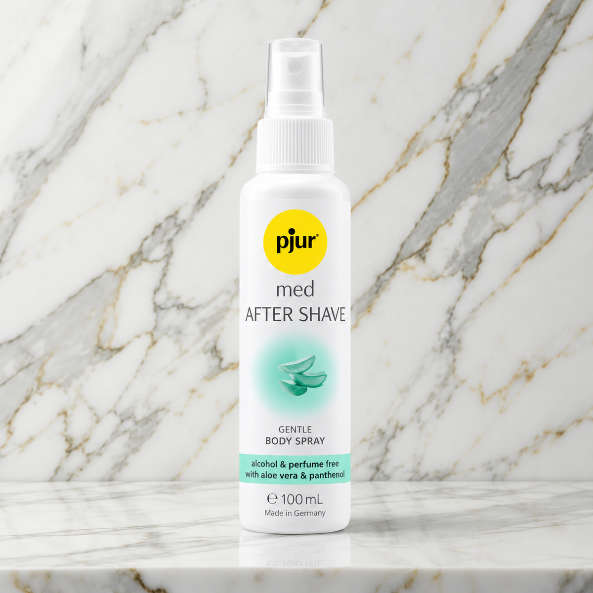 Witte sprayfles pjur med After Shave met geel logo op een marmeren plank