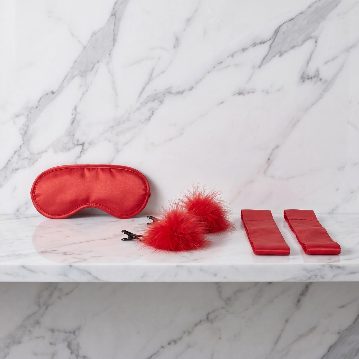 Rode blinddoek, satijnen banden en veren tepelklemmen op een marmeren plank, Amor kit