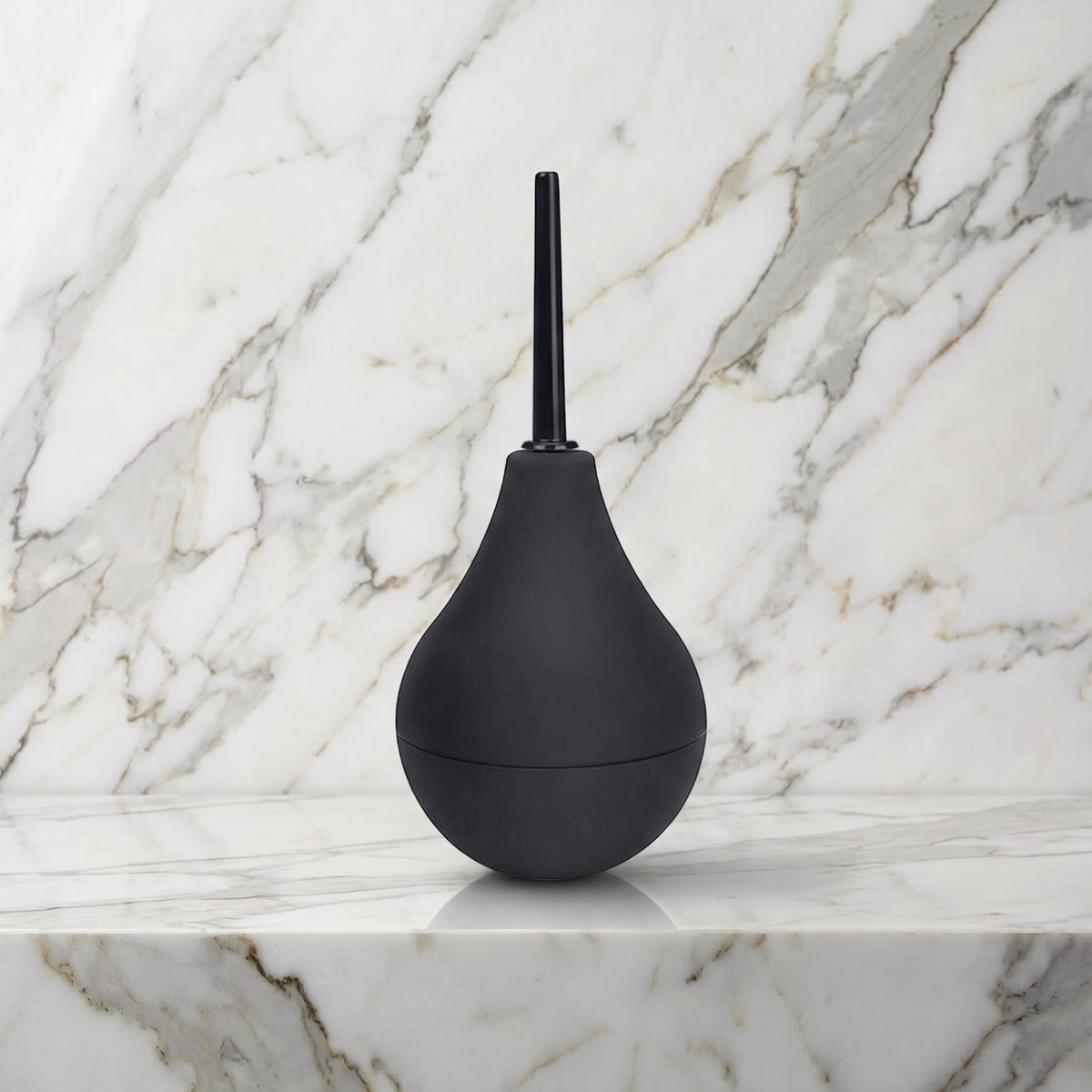 Zwarte anale douche met knijpbol en mondstuk rechtop op een marmeren plank, b-Vibe Anal Shower