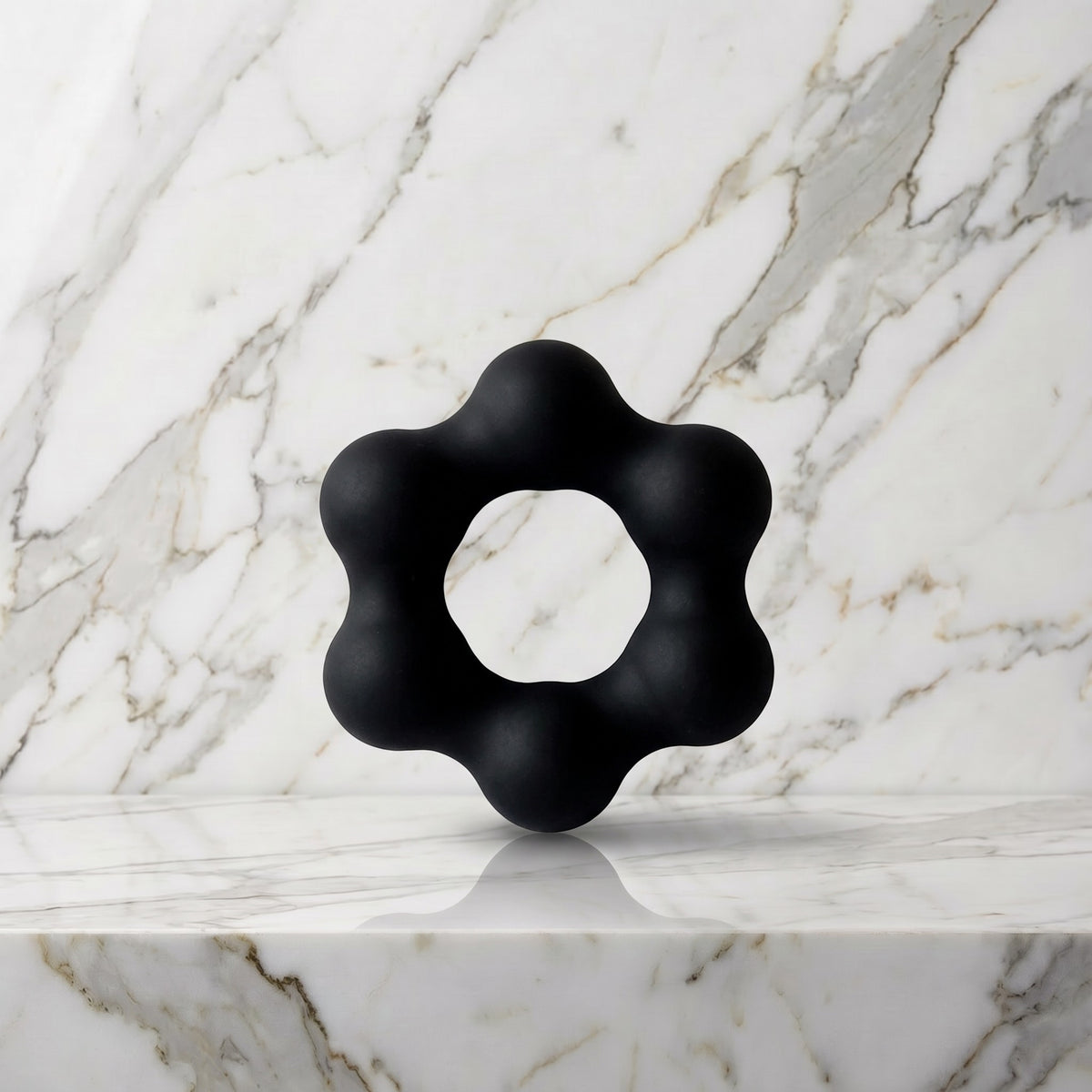 Zwarte Beaded Pleasure Ring cockring met zes balletjes rechtop op een marmeren plank