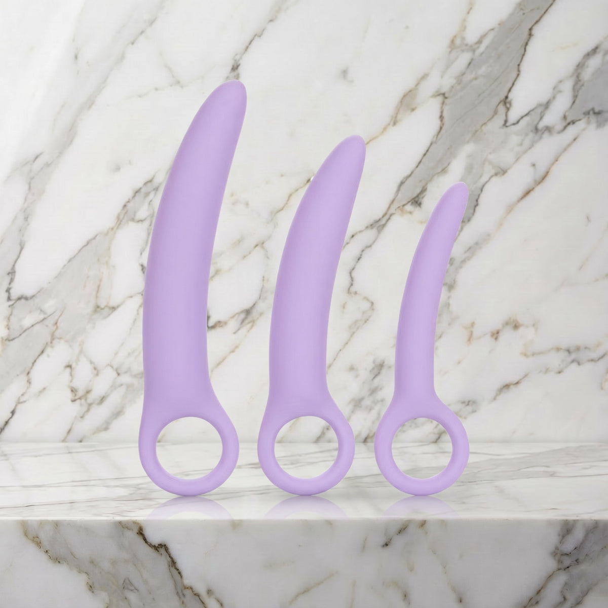 Drie lila siliconen dilators met ring als handvat rechtop op een marmeren plank, dilatorset van Dr. Berman