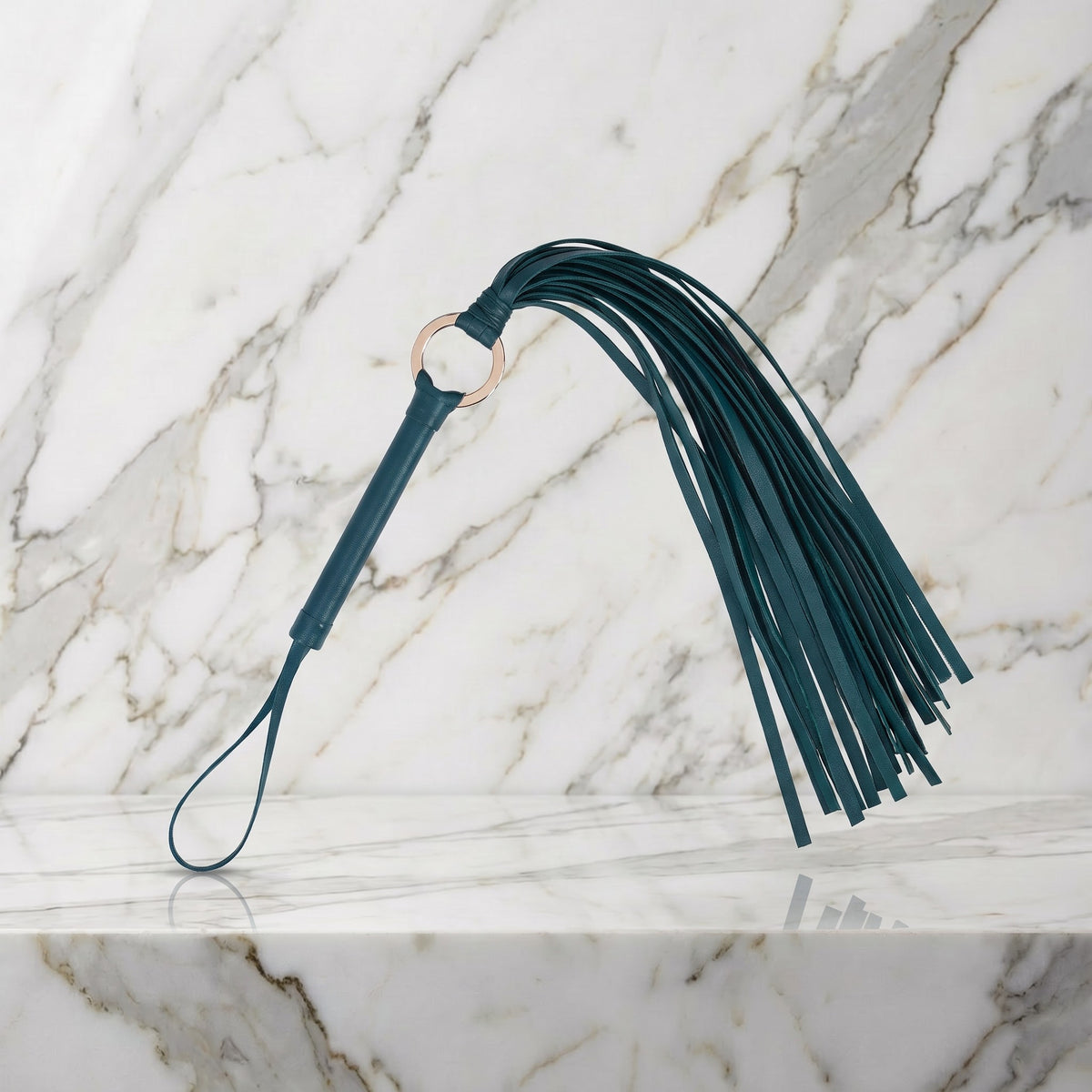 Groene flogger met 30 strengen en goudkleurige ring op een marmeren plank