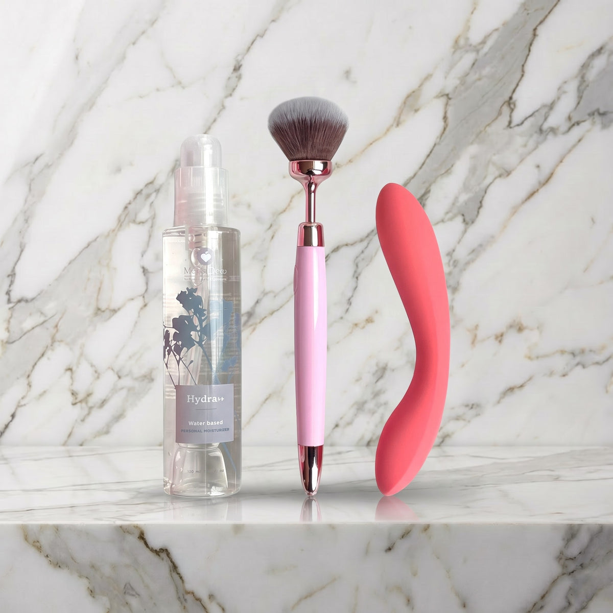 Gentle Sensations Kit op een marmeren plank: fles Hydra+ glijmiddel, roze vibrerende brush en koraalroze slanke vibrator