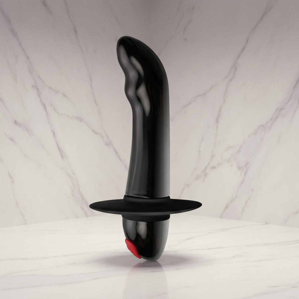 Zwarte Rocks-Off prostaatvibrator met rode knop rechtop op een lichte marmeren plank