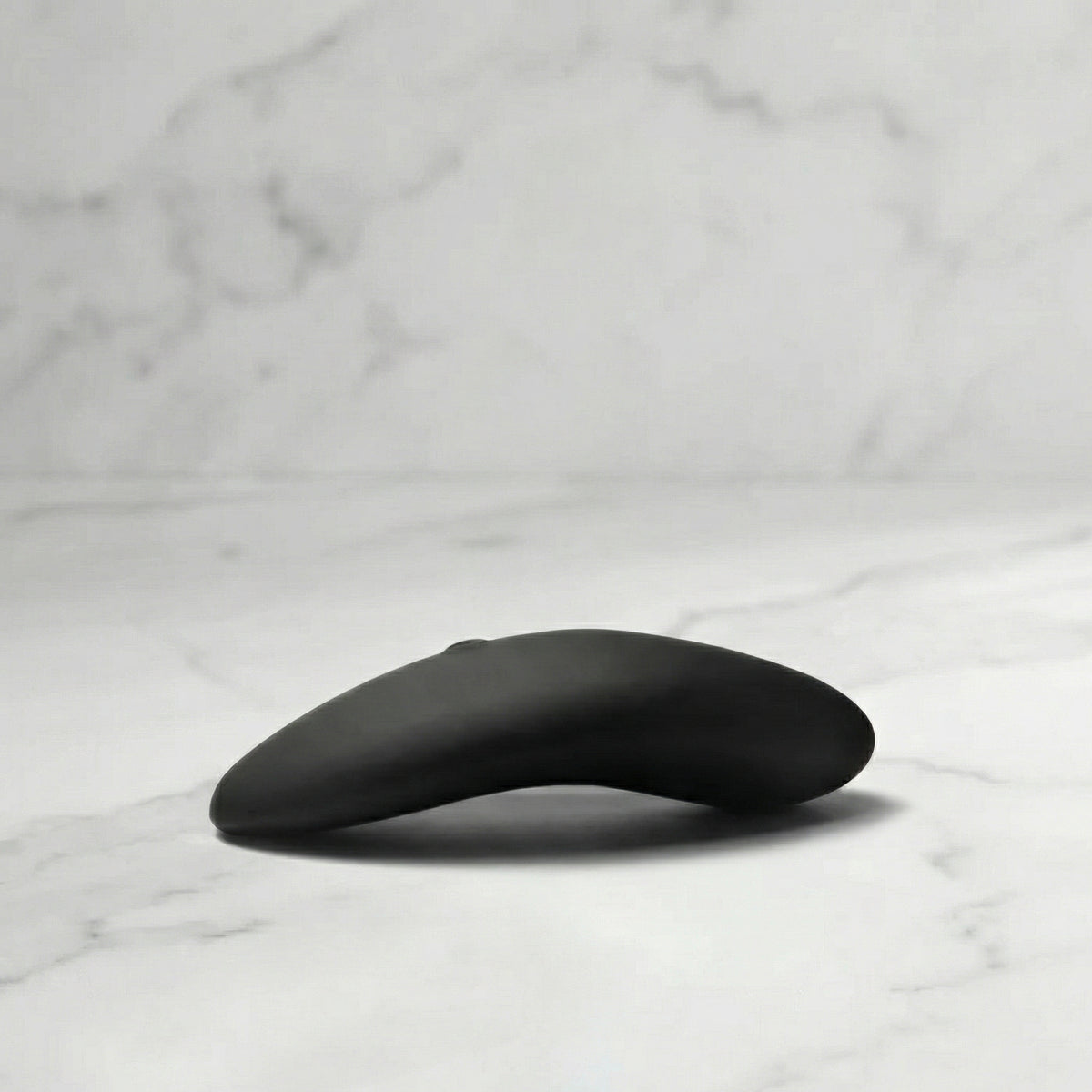 Zwarte Aludra stimulator met gebogen ergonomisch design op marmeren ondergrond