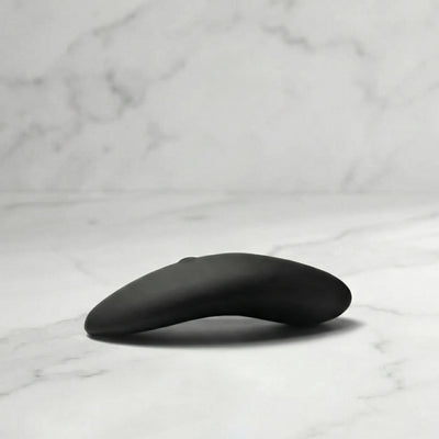 Zwarte Aludra stimulator met gebogen ergonomisch design op marmeren ondergrond