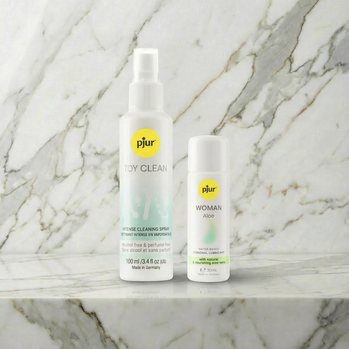 pjur Toy Clean sprayfles 100 ml en pjur Woman Aloe flesje 30 ml op een marmeren plank
