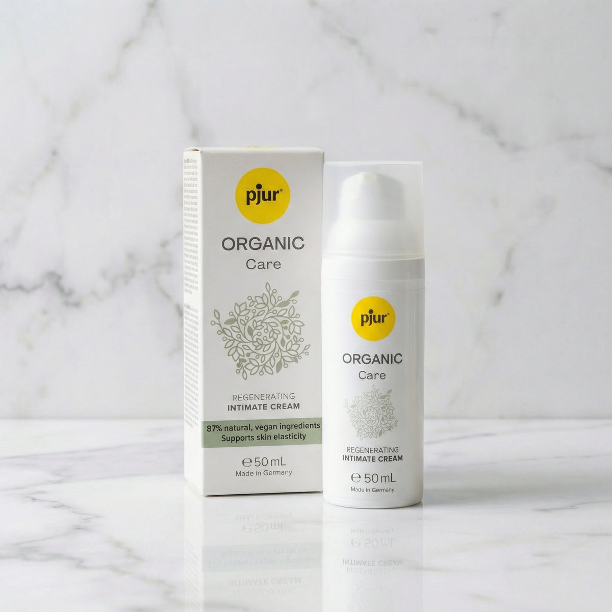 Witte pompflacon en doos pjur Organic Care intieme crème op een marmeren plank, 50 ml