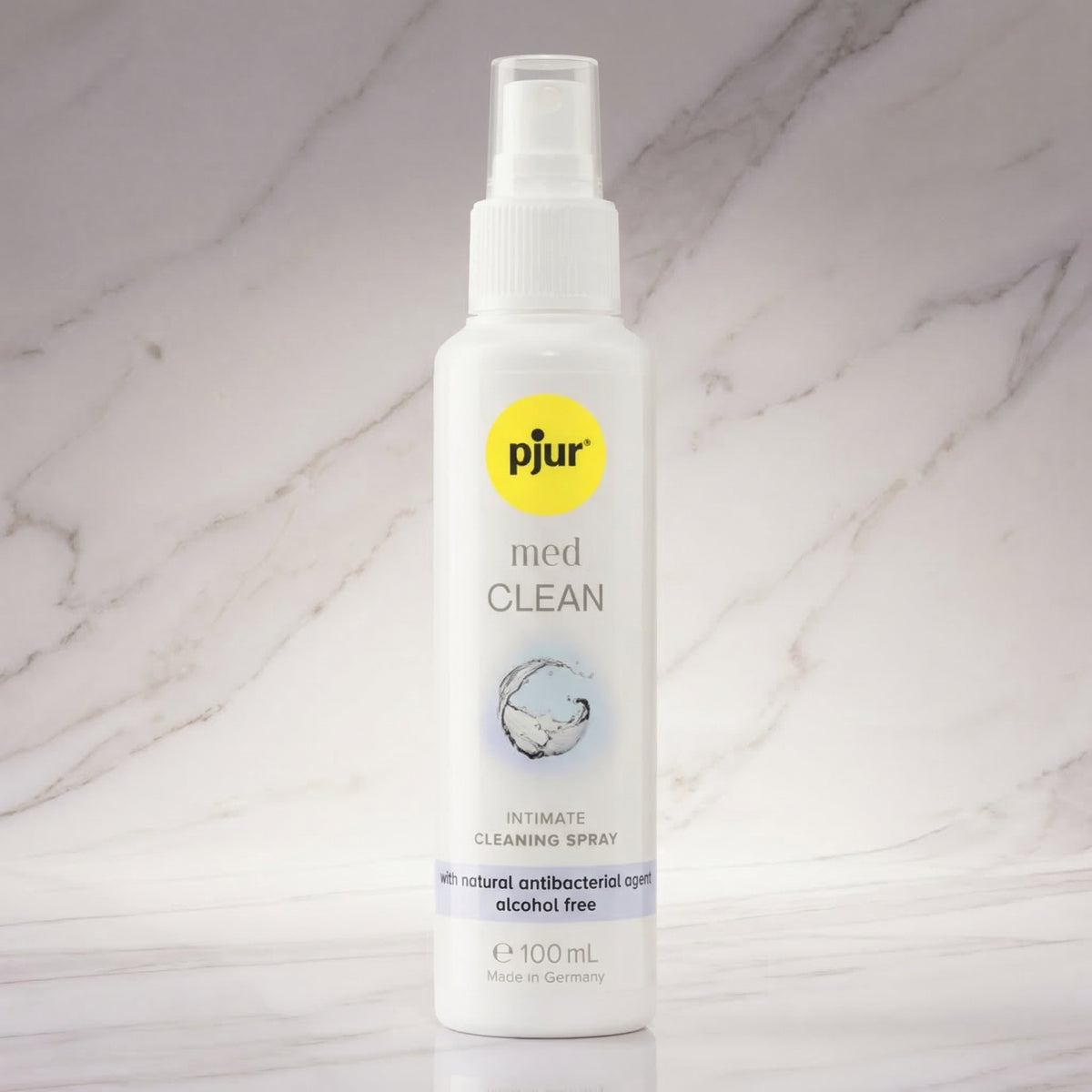 Witte sprayfles pjur med CLEAN 100 ml met gele dop-sticker op een marmeren plank