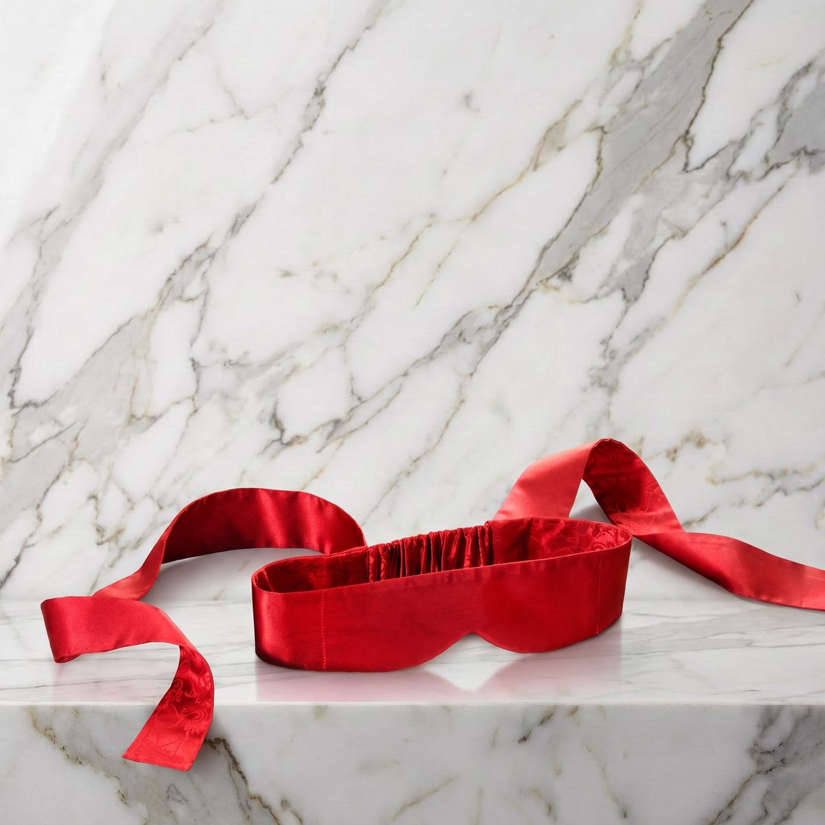 Rode zijden blinddoek met twee lange linten op een marmeren plank, Lelo Intima Silk