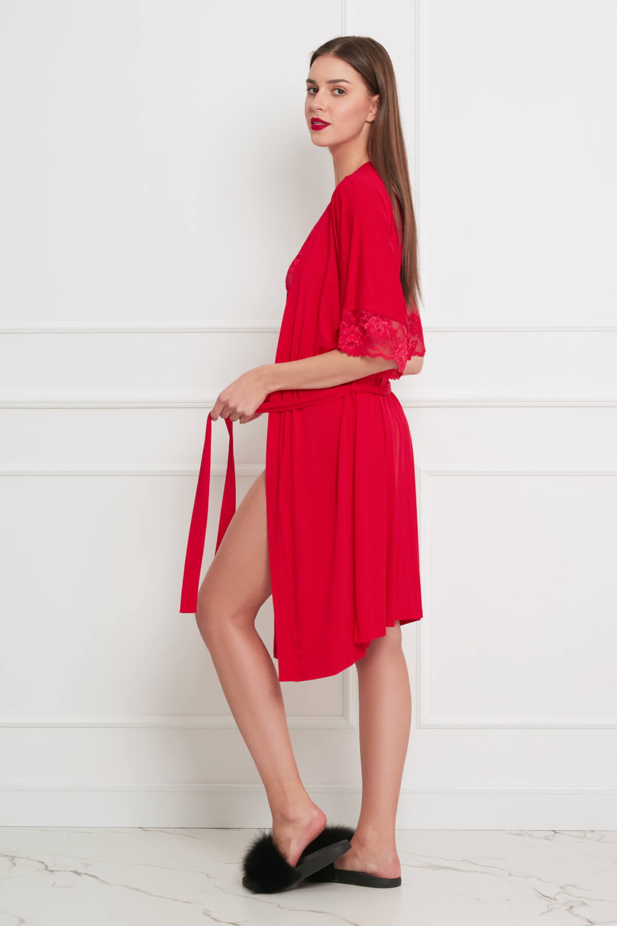 Model draagt rode kimono-ochtendjas met kanten mouwen en ceintuur, knielengte, zijprofiel
