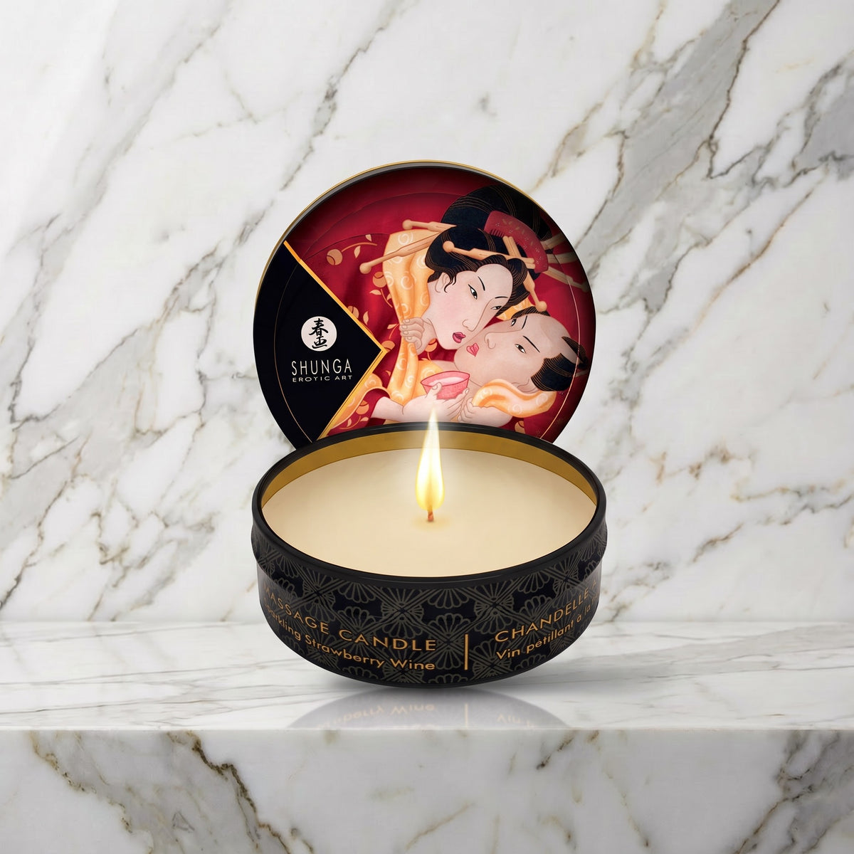 Shunga mini massagekaars Sparkling Strawberry Wine, open blikje met brandende kaars op een marmeren plank