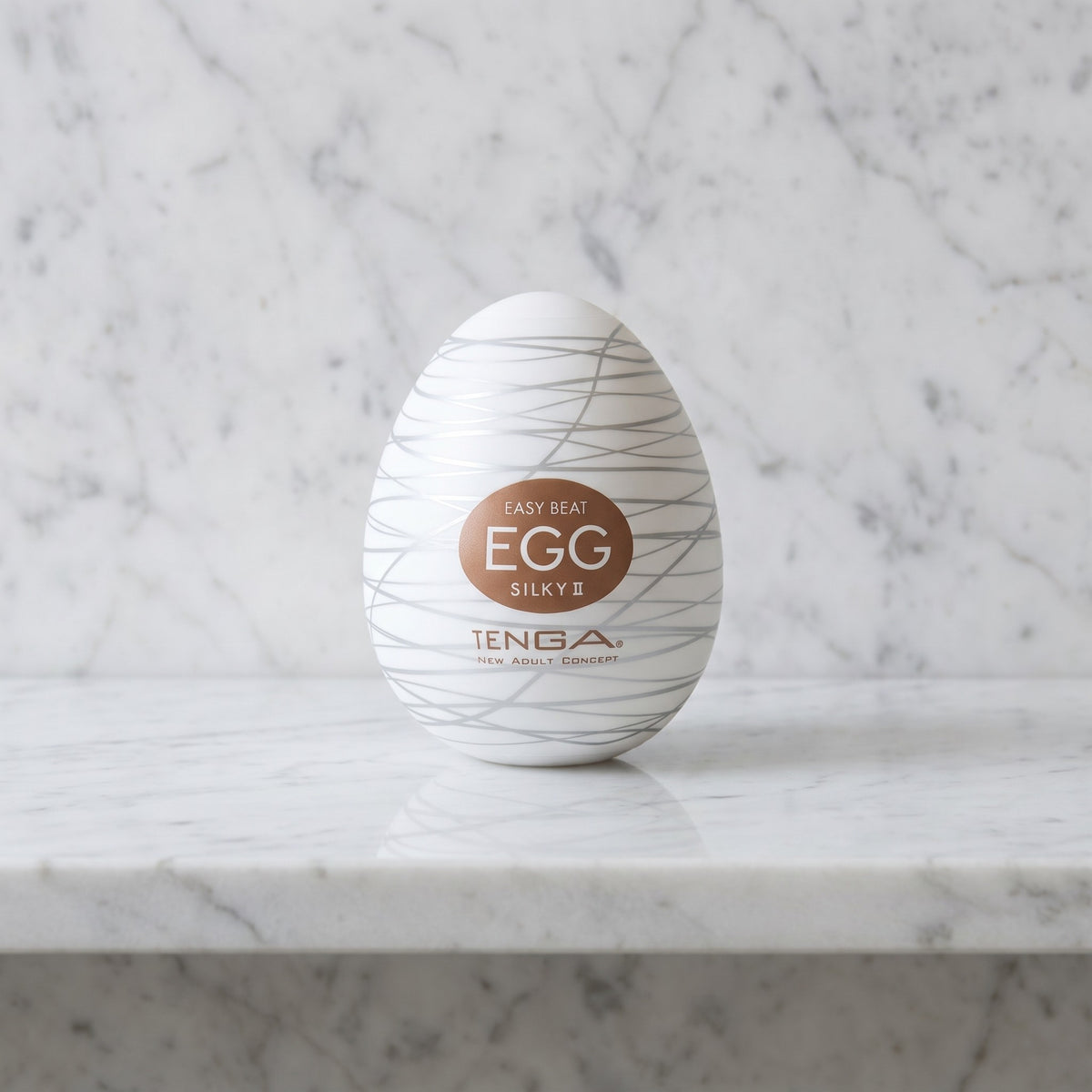 Wit masturbator-ei Egg Silky II met zilveren lijnen op een marmeren plank, Tenga
