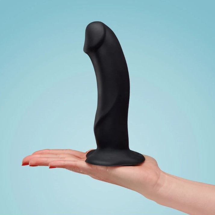The Boss dildo in zwart op handpalm, toont formaat ten opzichte van hand