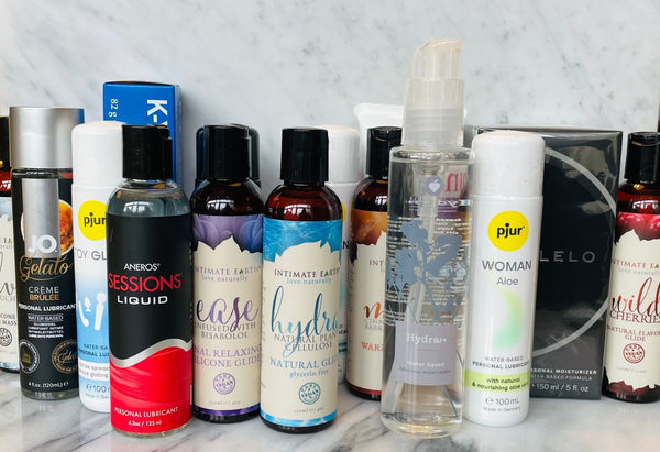 Verschillende glijmiddelen op waterbasis en siliconenbasis gepresenteerd op een marmeren ondergrond voor productoverzicht