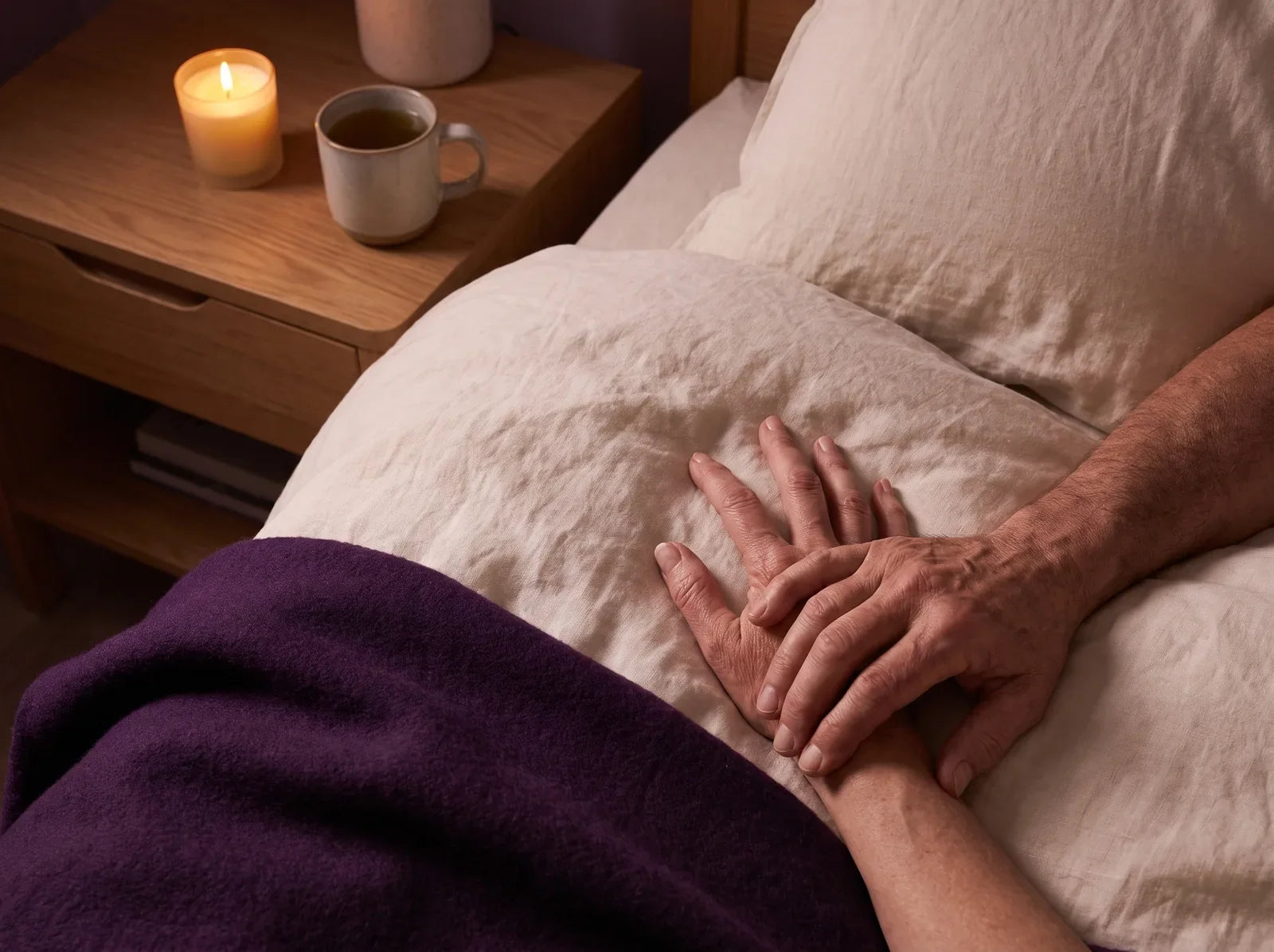 Sfeerbeeld: een oudere man legt zijn hand op die van zijn partner, bij kaarslicht