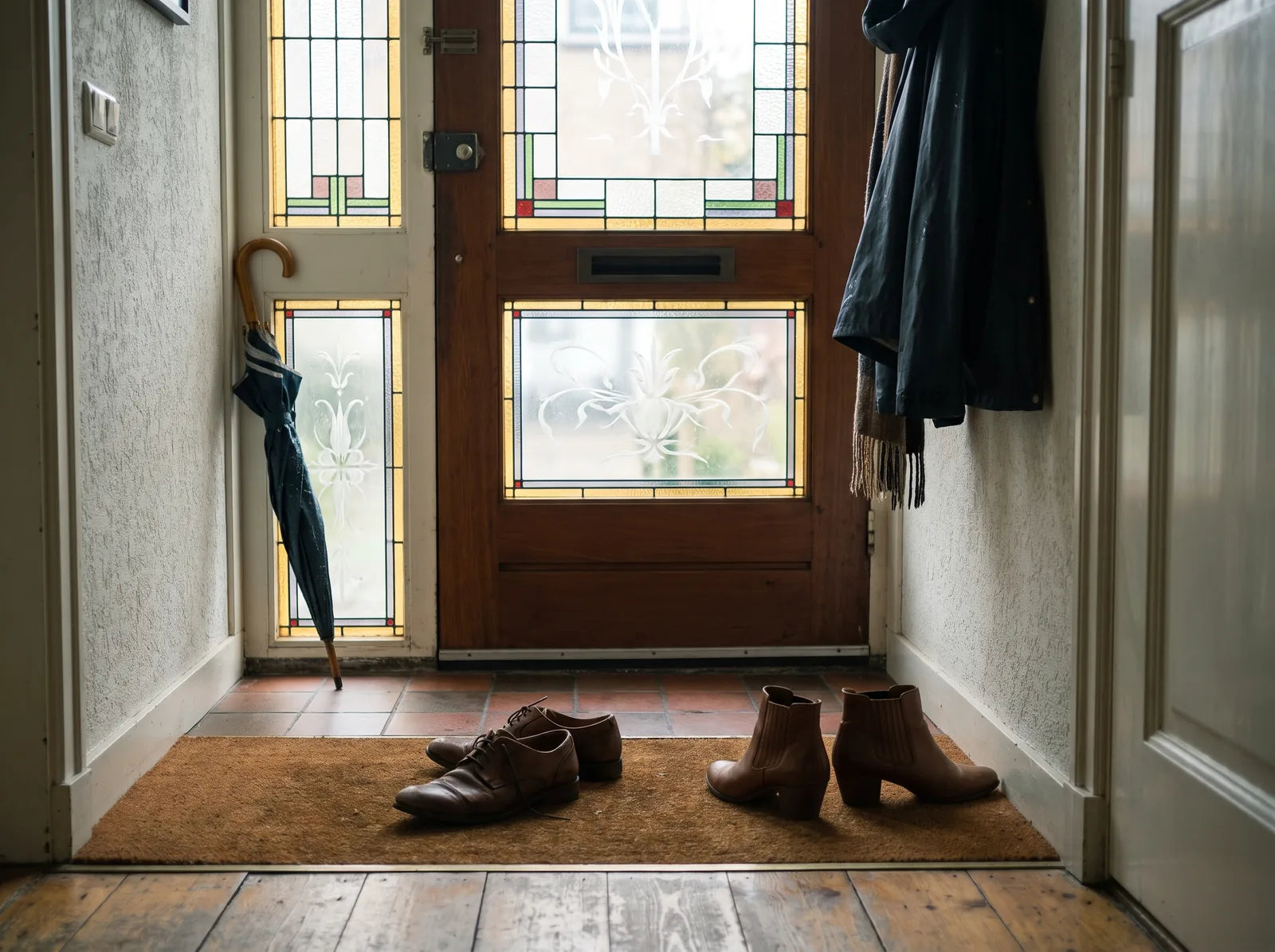 Sfeerbeeld: herenschoenen en damesschoenen naast elkaar op de deurmat in een Nederlandse gang