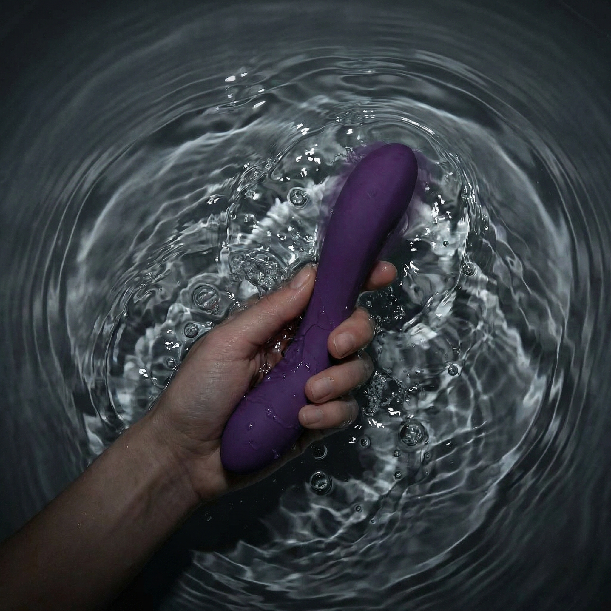 Hand houdt paarse vibrator vast in water ter illustratie van buzzy versus rumble vibraties