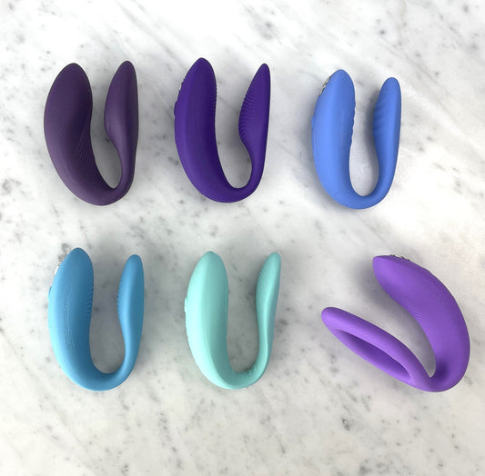 Zes U-vormige We-Vibe koppelvibratoren in paarse, blauwe, mintgroene en lila tinten op marmeren ondergrond