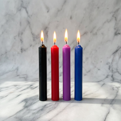 Vier brandende kaarsjes in zwart, rood, paars en blauw op een marmeren plank, Ouch!