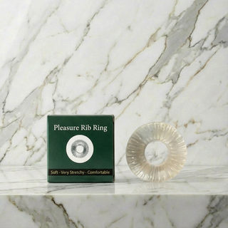 Doorzichtige geribbelde cockring Pleasure Rib Ring naast het groene doosje op marmer
