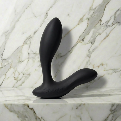 Zwarte Vector+ prostaatmassager staand op een marmeren plank, van We-Vibe