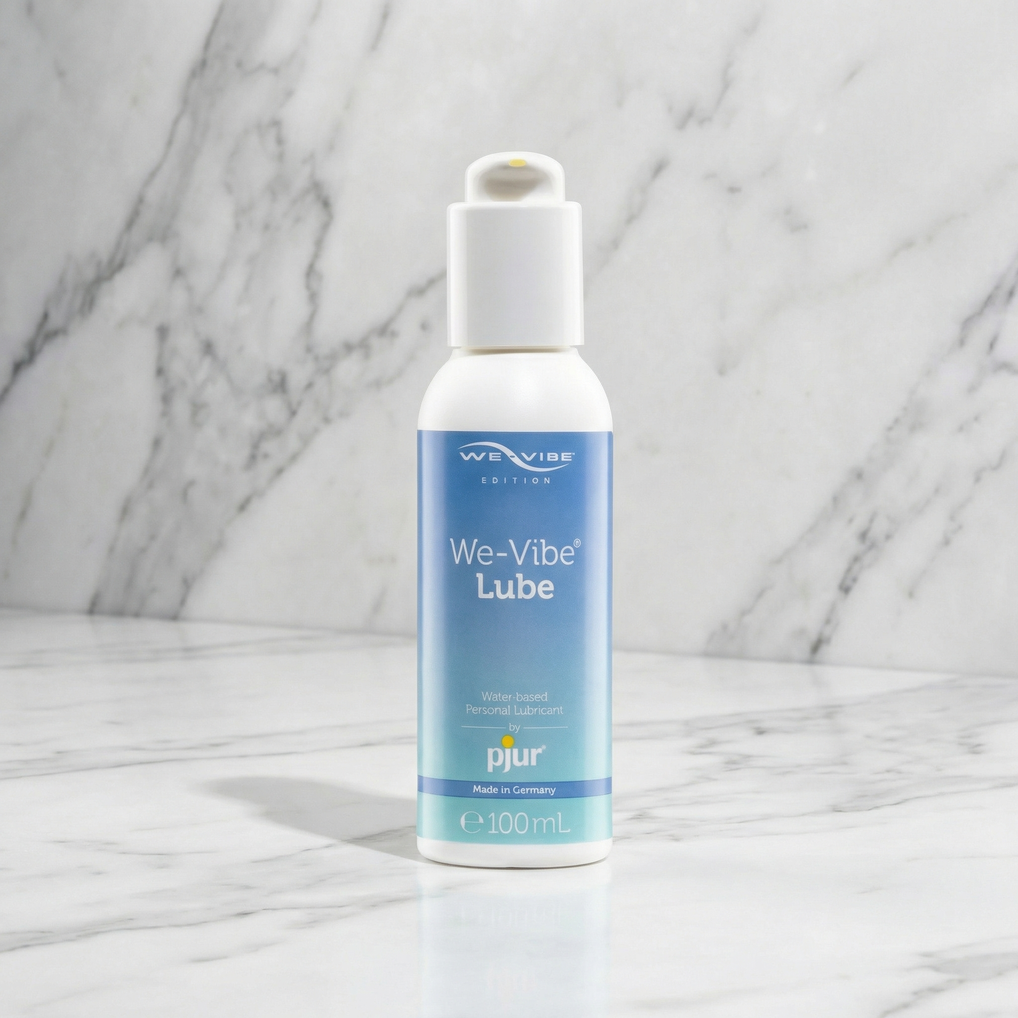 Fles We-Vibe Lube van pjur met wit pompje op een marmeren plank, 100 ml glijmiddel op waterbasis