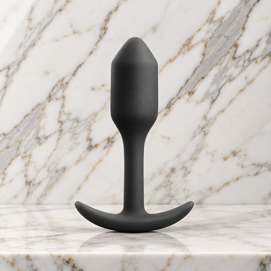 Zwarte Snug Plug rechtop op een marmeren plank, buttplug van b-Vibe