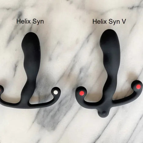 Helix Syn en Helix Syn V naast elkaar op marmer, de V met knop onderaan, Aneros