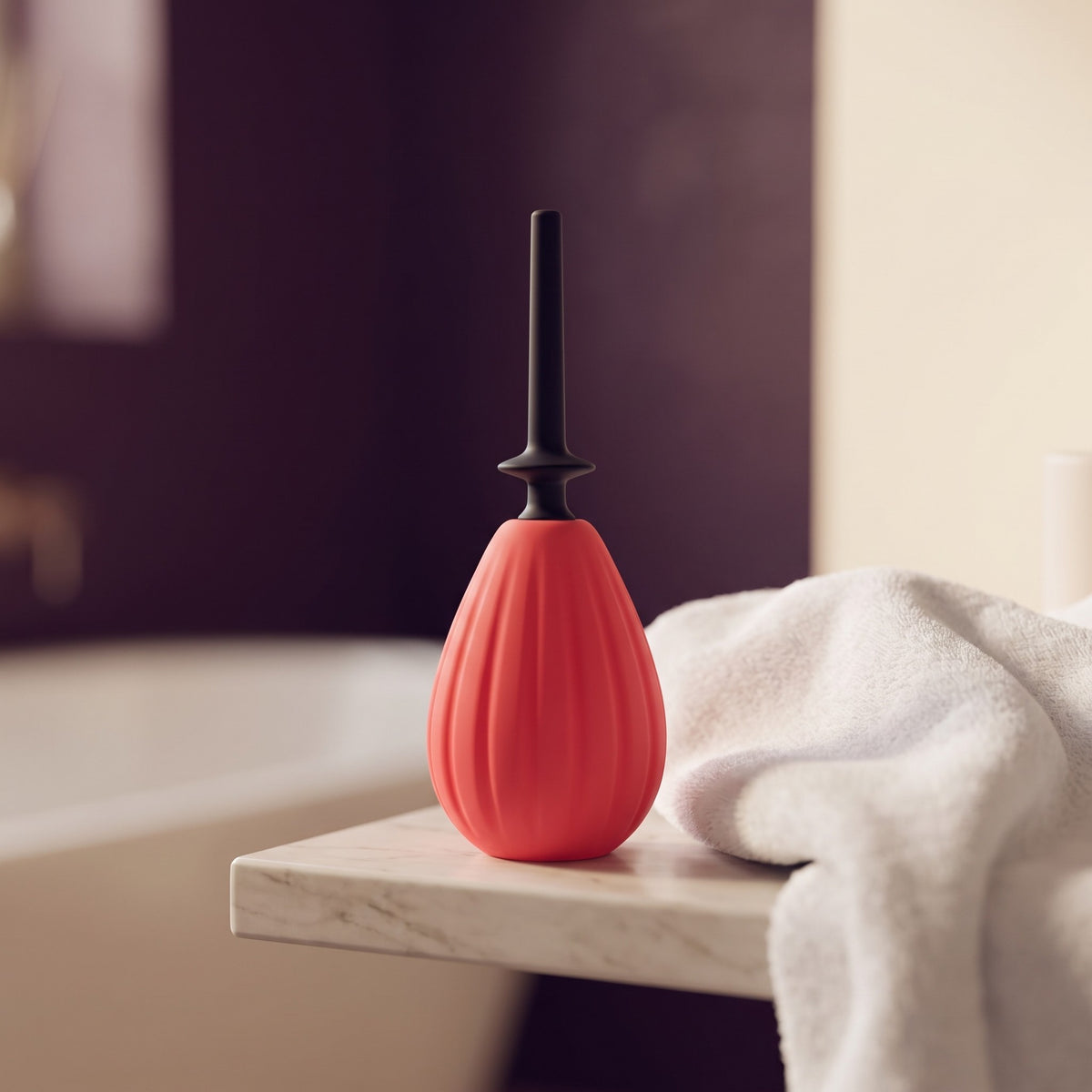 Sfeerbeeld: rode Aneros Prelude anale douche op een badkamerplank naast een witte handdoek