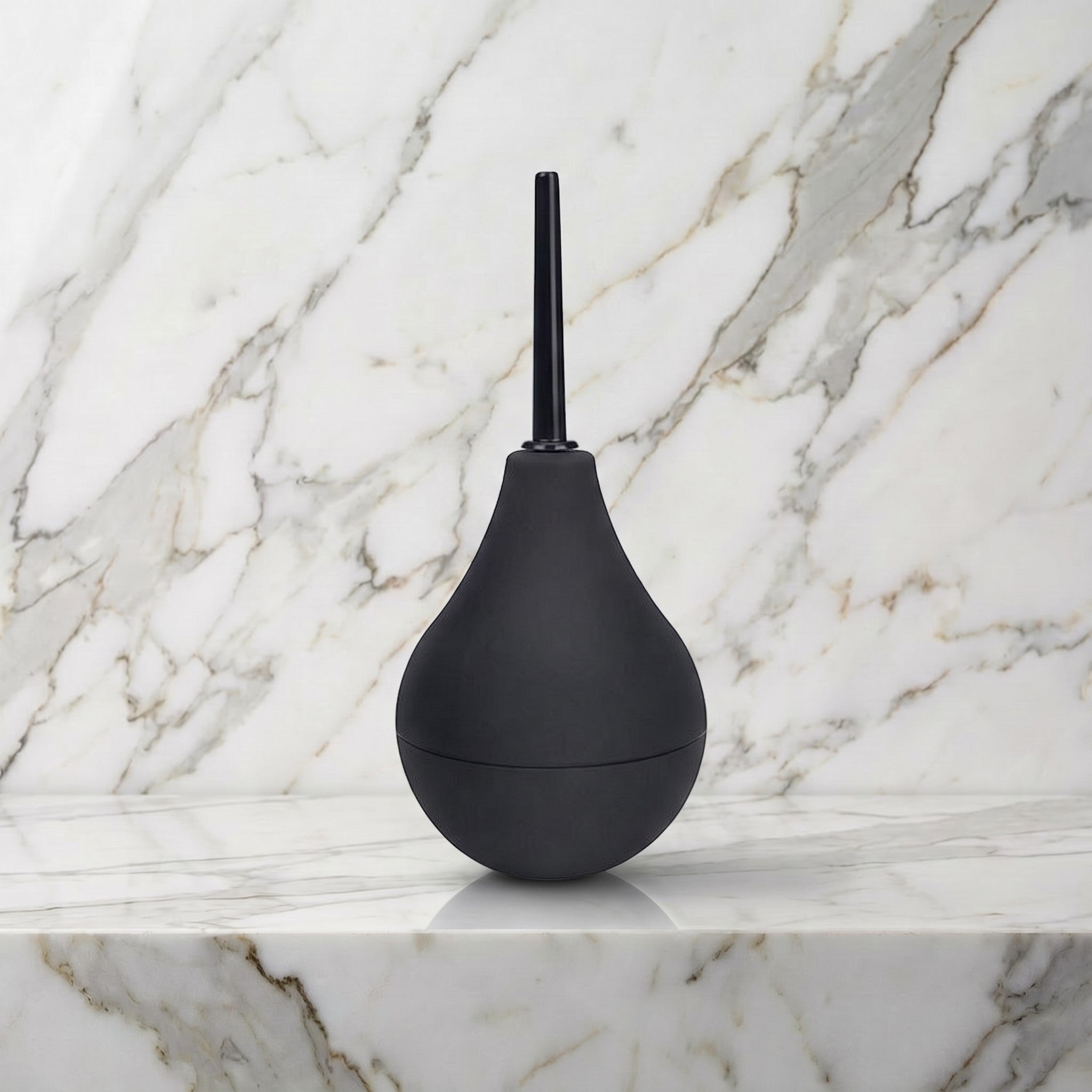Zwarte anale douche met knijpbol en mondstuk rechtop op een marmeren plank, b-Vibe Anal Shower