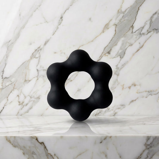 Zwarte Beaded Pleasure Ring cockring met zes balletjes rechtop op een marmeren plank