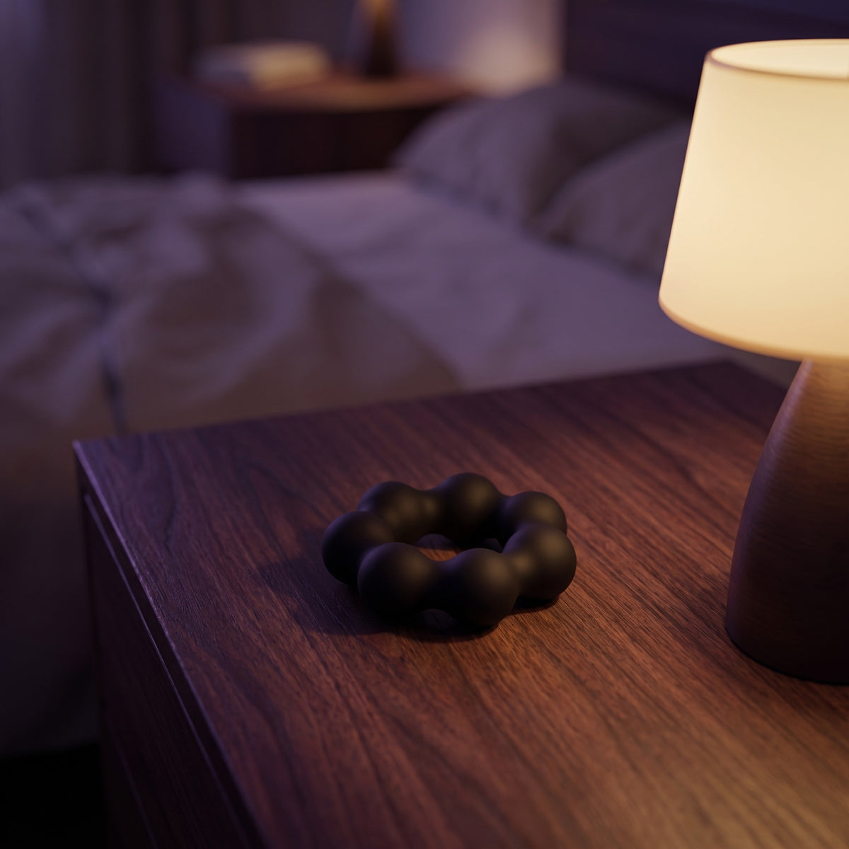Sfeerbeeld: zwarte Beaded Pleasure Ring op een houten nachtkastje naast een lamp