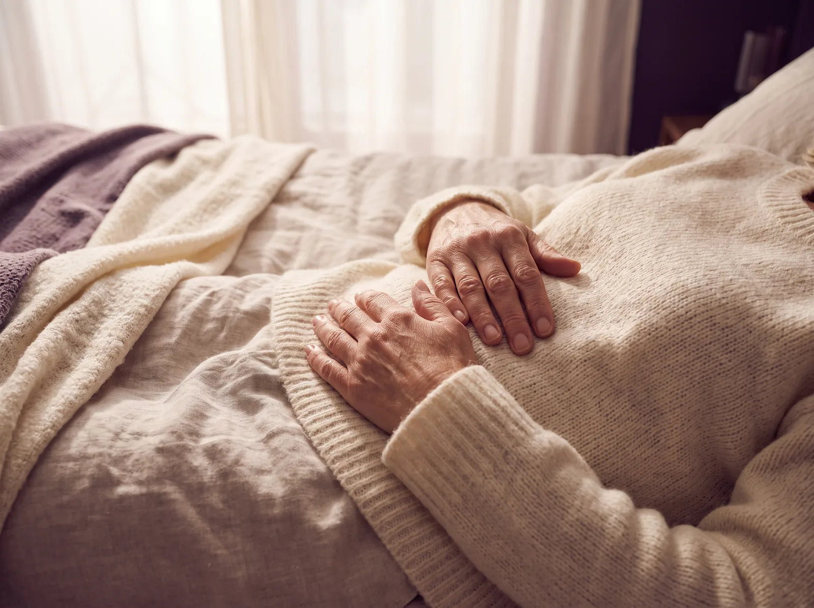Sfeerbeeld: een vrouw ligt op bed met haar handen op haar buik en voelt haar adem