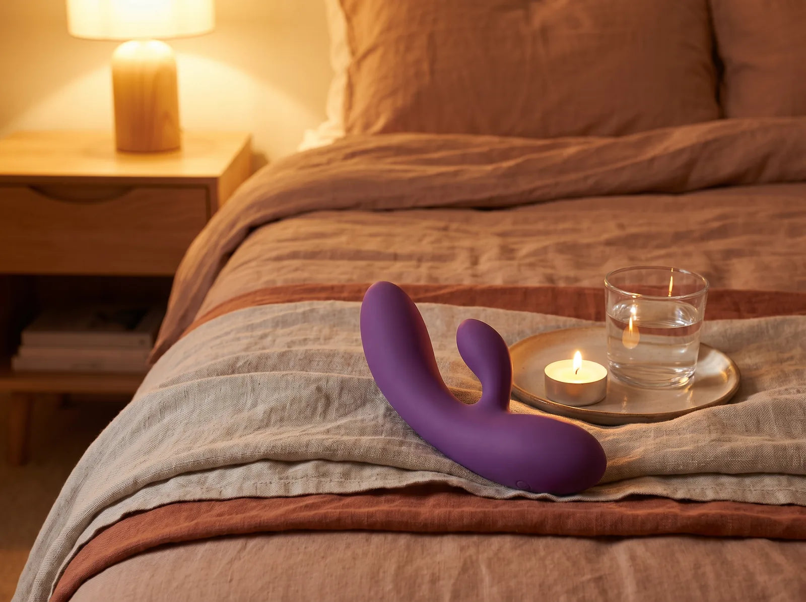 Sfeerbeeld: de Yed Prior rabbit vibrator ligt op een linnen plaid op bed bij kaarslicht