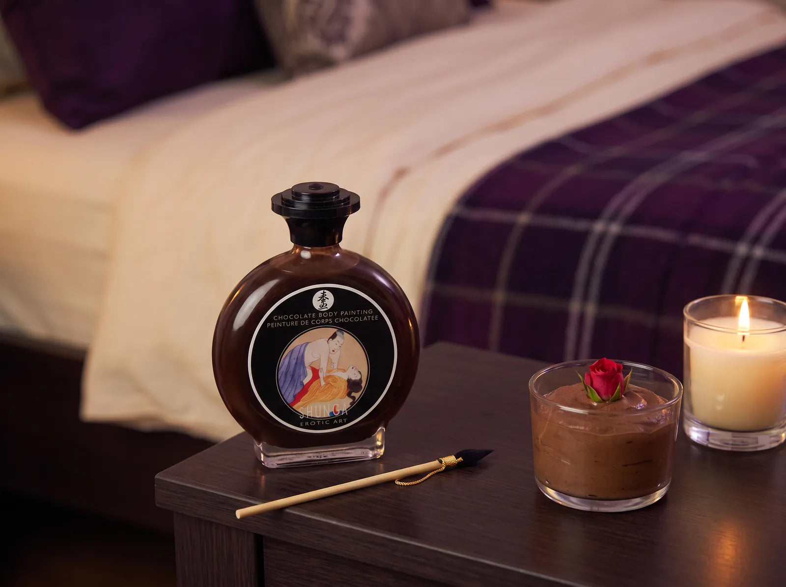 Sfeerbeeld: Shunga chocolade bodypaint met penseeltje naast een glas mousse op een nachtkastje