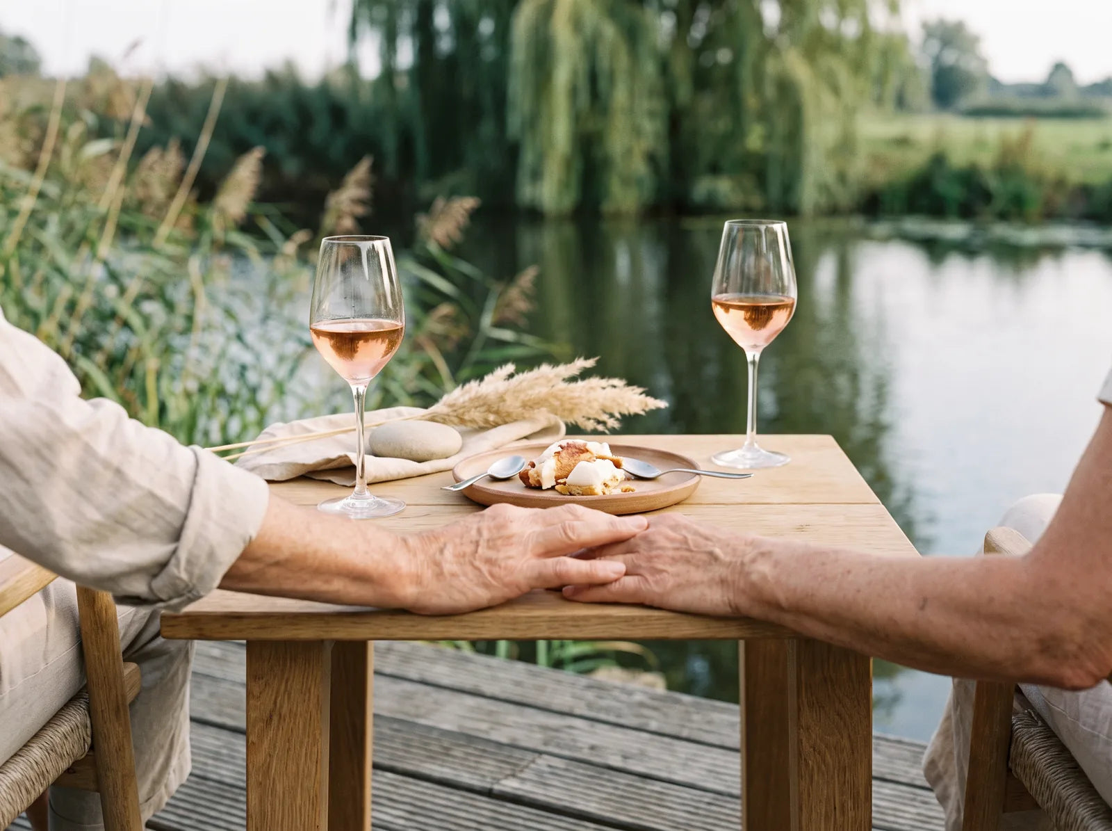 Sfeerbeeld: twee glazen rosé en een gedeeld dessert op een terras aan het water