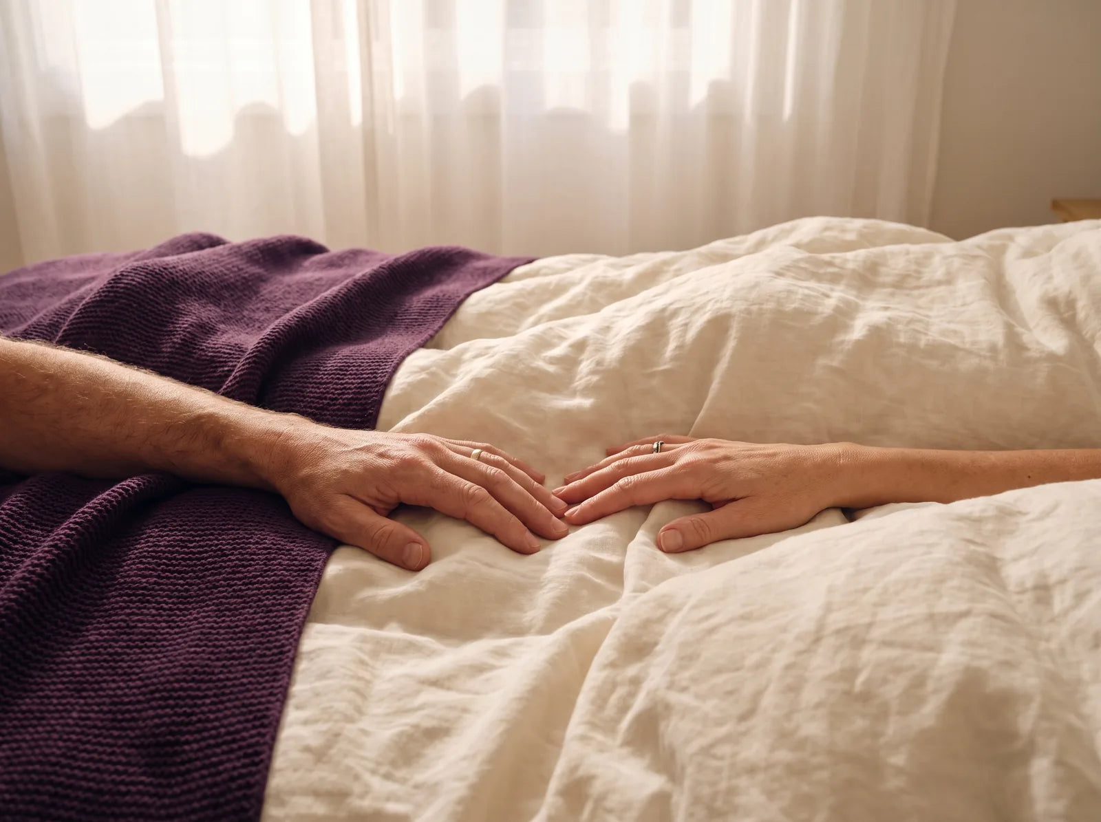 Sfeerbeeld: de handen van een man en een vrouw op een dekbed, dicht bij elkaar