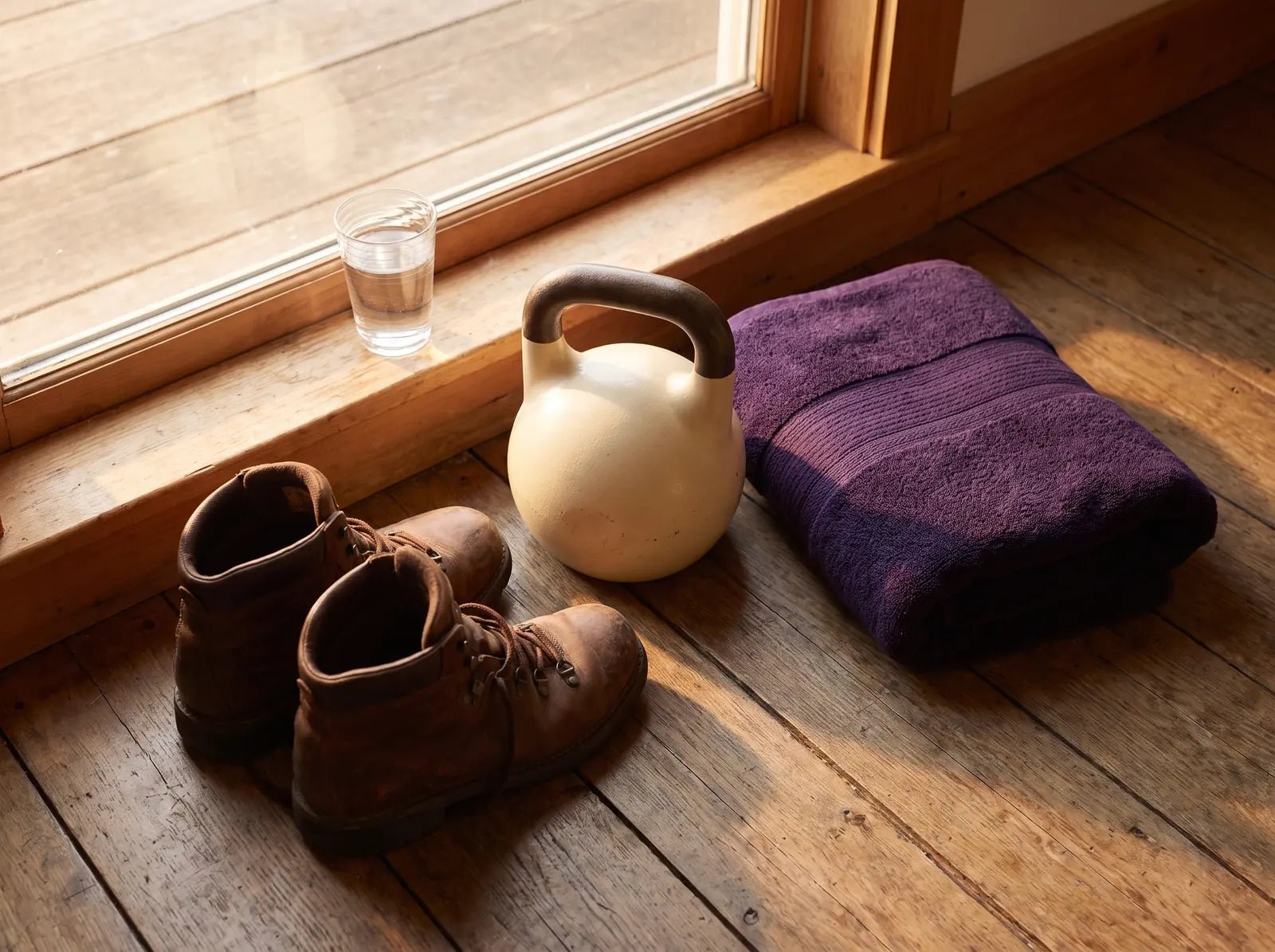 Sfeerbeeld: wandelschoenen, een kettlebell en een handdoek bij het raam in de ochtend