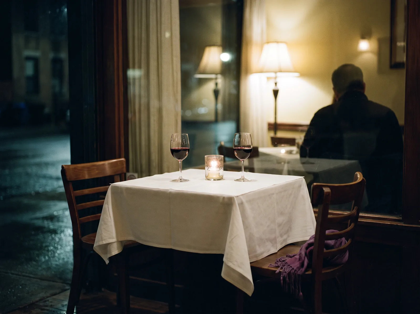 Sfeerbeeld: een tafeltje voor twee met rode wijn en een kaarsje in een rustig restaurant