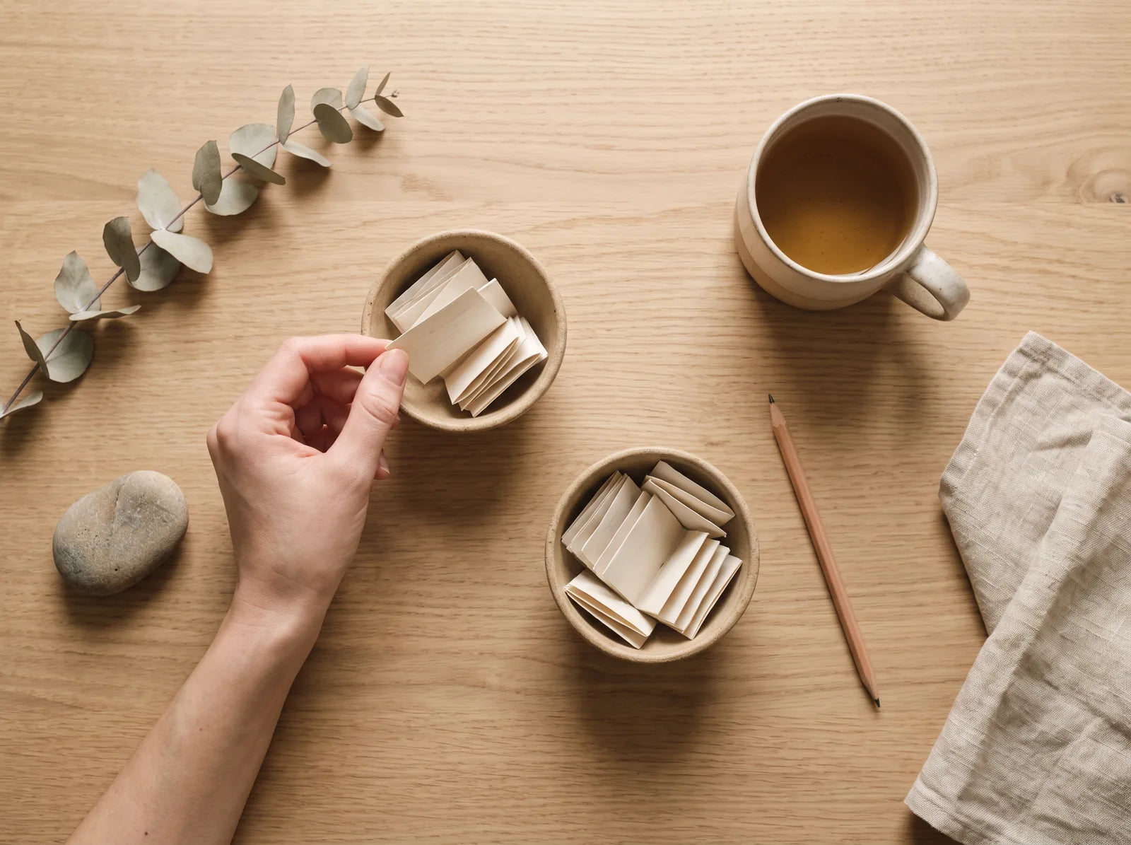 Sfeerbeeld: twee schaaltjes met opgevouwen briefjes vol wensen op een houten tafel