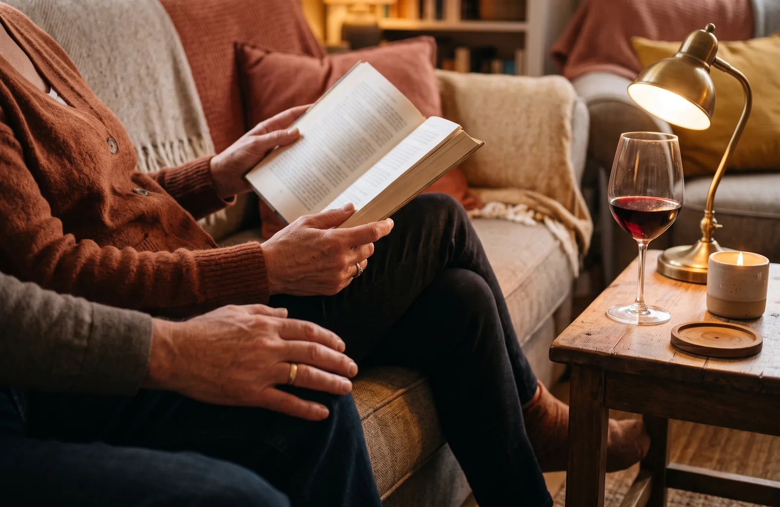 Sfeerbeeld: voorlezen uit een boek op de bank, met een glas rode wijn