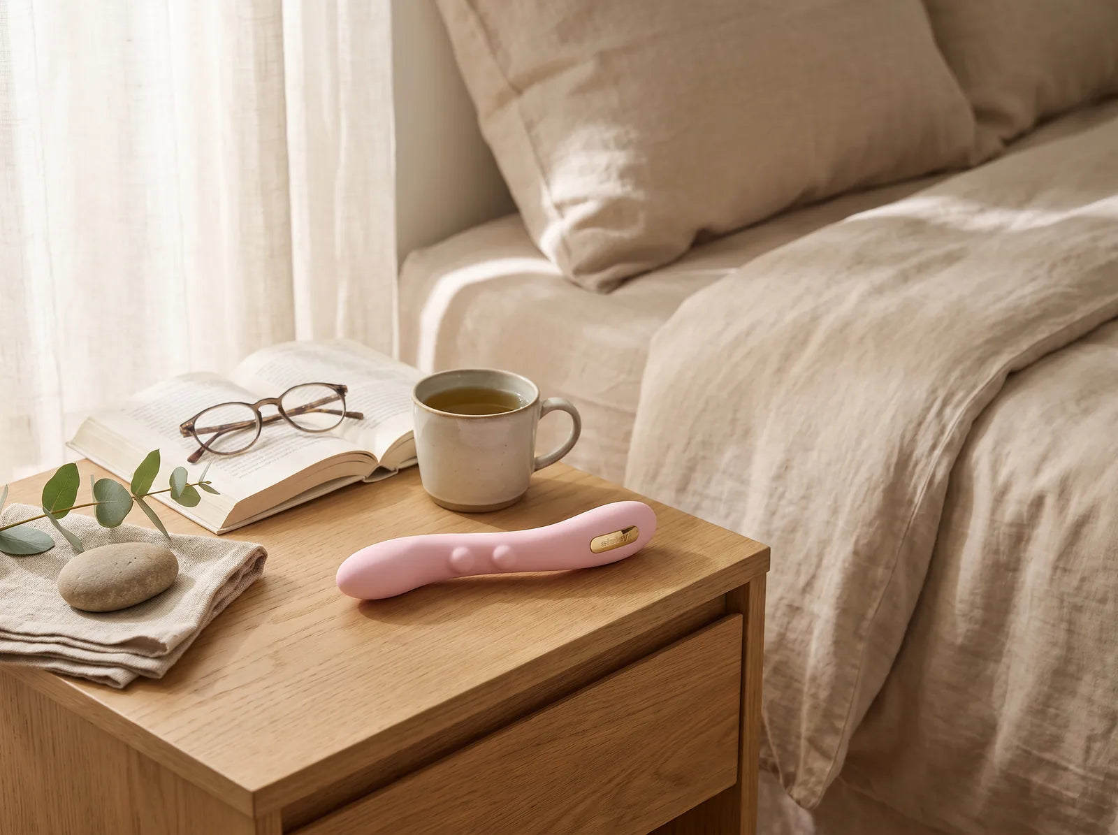 Sfeerbeeld: de Sisley staafvibrator ligt op een houten nachtkastje naast een boek, een leesbril en thee