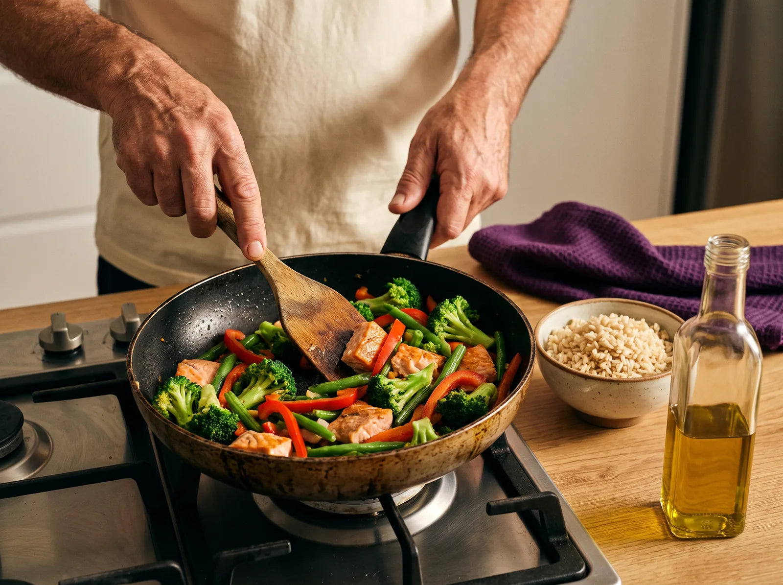 Sfeerbeeld: man roerbakt zalm met broccoli, paprika en sperziebonen, met zilvervliesrijst ernaast