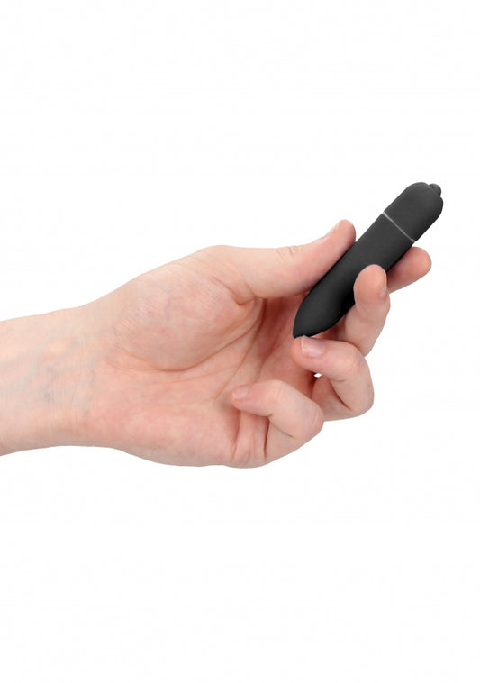 Hand die een kleine zwarte bullet vibrator vasthoudt tegen witte achtergrond
