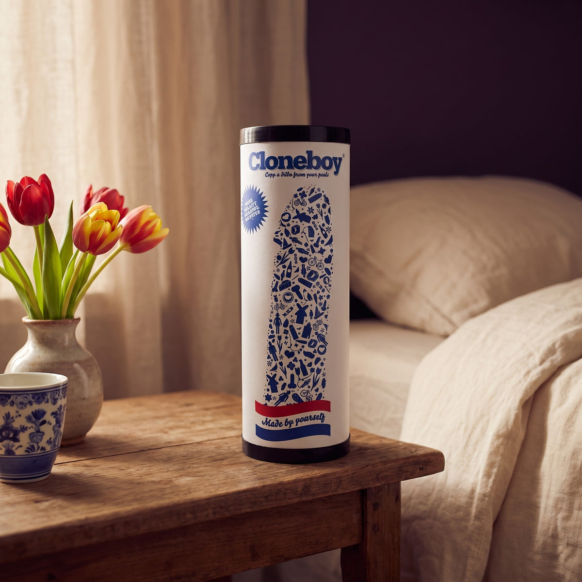 Sfeerbeeld: Cloneboy koker op een houten nachtkastje naast tulpen en een Delfts blauw kopje