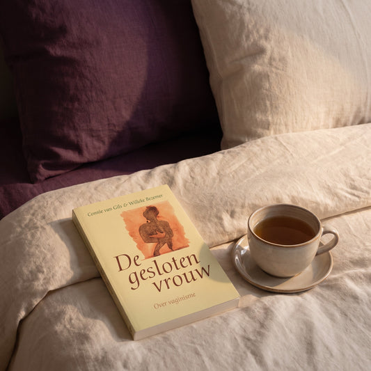 Sfeerbeeld: De gesloten vrouw op een bed met creme linnen naast een kop thee
