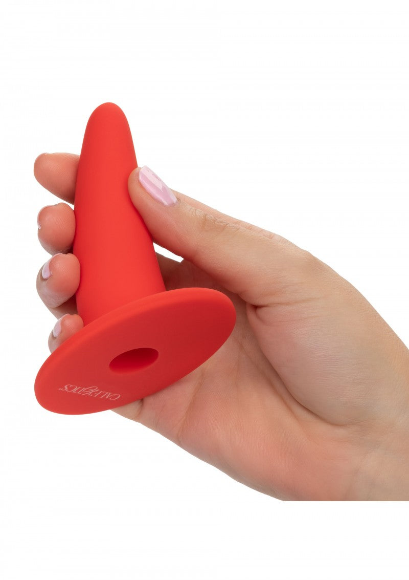 Hand houdt de grootste rode dilator vast, met de platte ronde voet in beeld