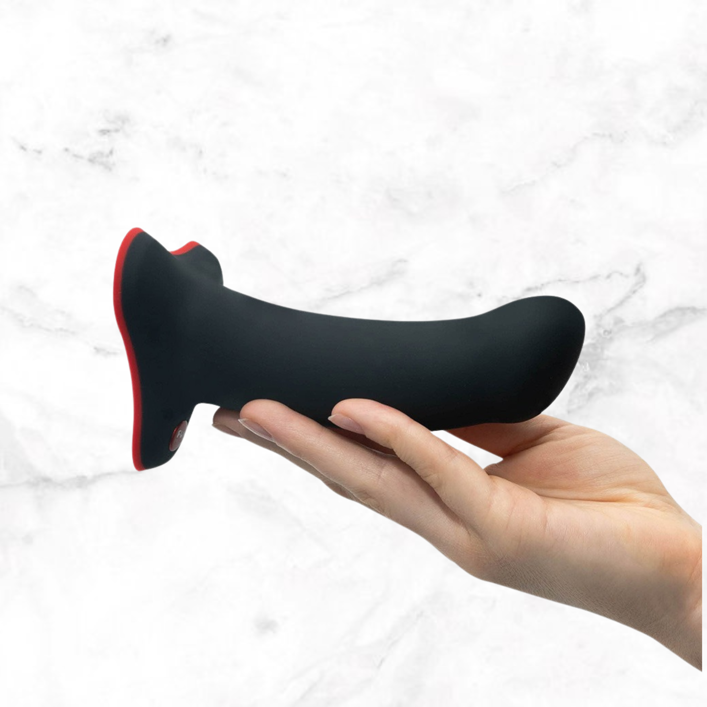 Zwarte Fun Factory Amor dildo met rode voet liggend op een open hand