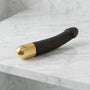 Zwarte semi-realistische vibrator met gouden onderkant op een marmeren plank, Dorcel Real Vibration M